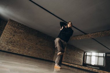 Tuğla duvarlı geniş bir şehir stüdyosunda dans eden bir dansçı..