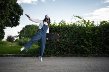 Kot pantolon giyen bir patenci, iyi havada güvenli bir şekilde uzun bir kaykaya biner..