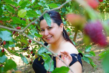 Güzel Latin asıllı Guatemalalı kadın böğürtlen ağaçlarının arasında gülümsüyor