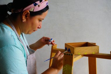 Evdeki ahşap mobilyaların üzerine resim yapan bir kadın, DIY projesi.