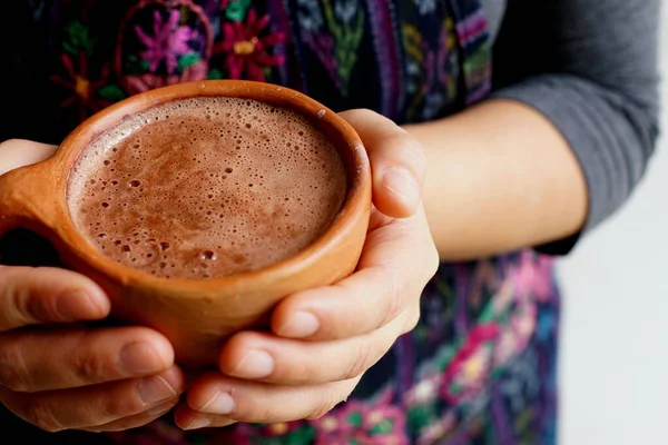 stock image Frothy Guatemalan traditional hot chocolate in a clay cup held by hand