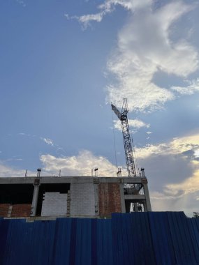 İnşaat vinçleri ve mavi gökyüzünün altındaki bina