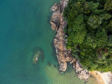 Dungun, Terengganu 'daki uçurumlar ve yeşil ağaçlarla çevrili boş bir sahil manzarası..