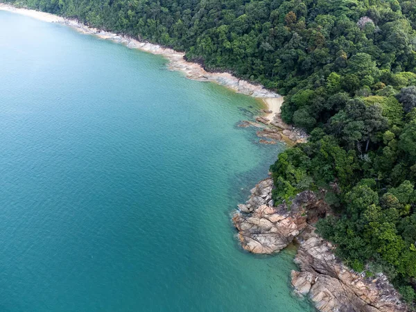 Dungun, Terengganu 'daki uçurumlar ve yeşil ağaçlarla çevrili boş bir sahil manzarası..