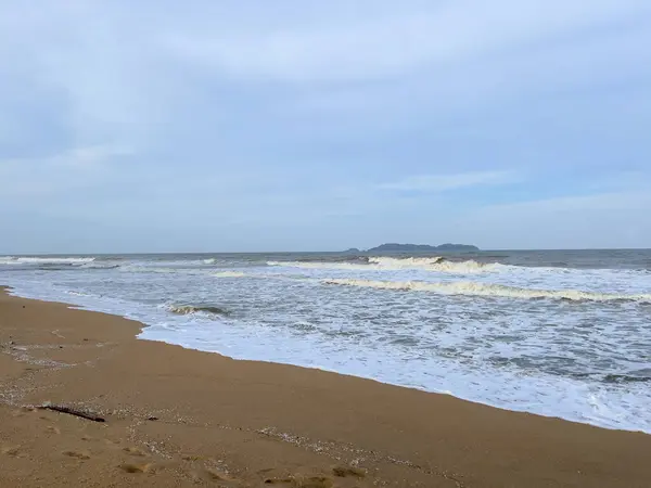 A view of a calm beach with wind waves hitting the beach in the monsoon season and cloudy skies in Marang, Terengganu.