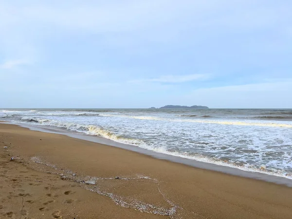 A view of a calm beach with wind waves hitting the beach in the monsoon season and cloudy skies in Marang, Terengganu.
