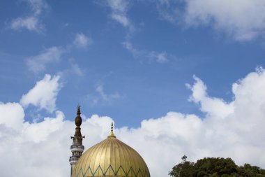 İslami mimarinin özü, karmaşık geometrik desenlerle süslenmiş altın bir kubbe ve hilal tarafından taçlandırılmış ince bir minaredir..