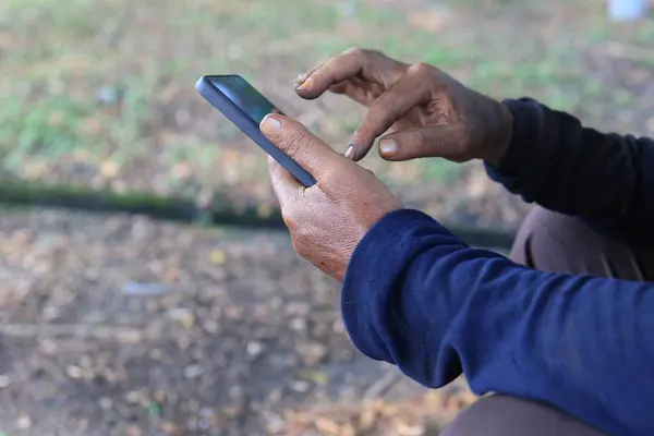 Doğal bir ortamda akıllı telefonu tutan bir insanın detaylı görüntüsü, günlük hayatta modern bağlantı ve teknoloji entegrasyonunu vurguluyor..