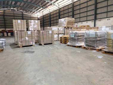 Perak, Malezya - 31 Temmuz 2025: Yığınla paletler, karton kutular ve endüstriyel raflarla dolu geniş bir depo.