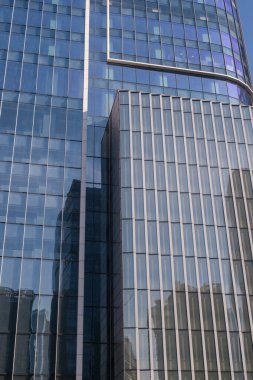 Çevredeki binaları yansıtan modern cam gökdelen manzarası