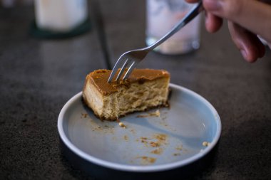 Bir kadının eli çatalla pasta keser..