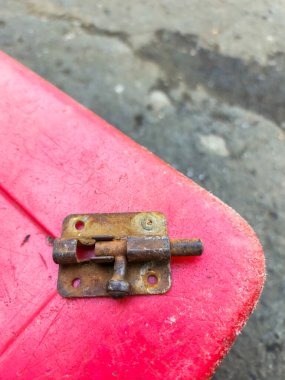 Kırmızı plastiğin üzerindeki paslı demir kapı mandalı. Demir ve demir alaşımları, oksitlenme olarak bilinen kimyasal bir reaksiyon yüzünden paslanır. Demir neme veya oksijene maruz kaldığında, oksitlenme meydana gelir..