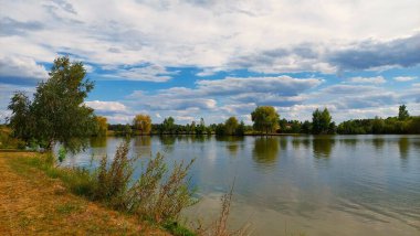 Etrafında orman ve bulutlar olan bir göl.