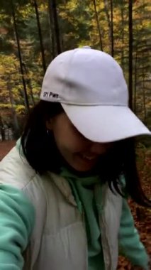 Sonbahar ormanında duran kadın güz mevsimi yürüyüşünün tadını çıkarıyor.