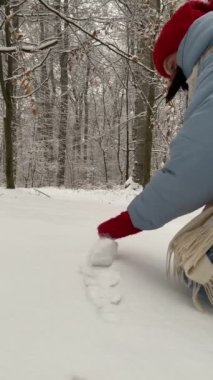 Kardan adam yapan kadın kartopunu yuvarlıyor.