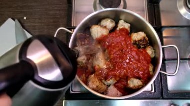 cooking meatballs in tomatoes sauce overhead view domestic kitchen