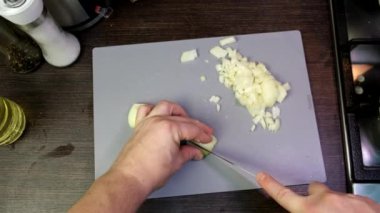 pov males hand chopping onions on cut board overhead view