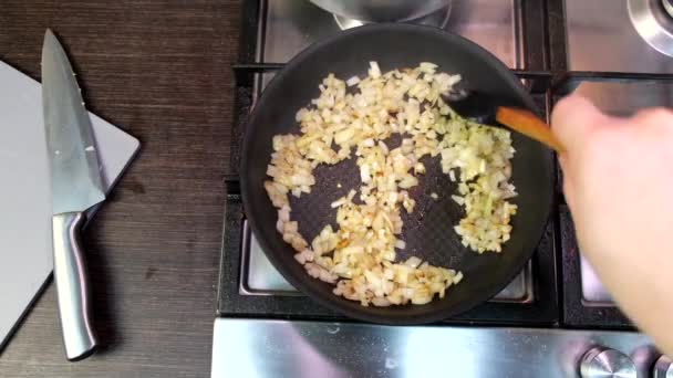 フライパンに玉ねぎを炒める家庭用キッチンストーブの上からの眺め — ストック動画