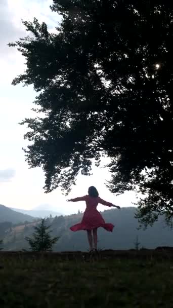 カルパチア山脈の大きなオークの木の下を走る赤いドレスの幸せな美しい女性ウクライナ — ストック動画