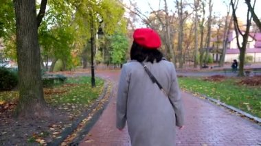 happy beautiful woman walking by autumn public park spinning around