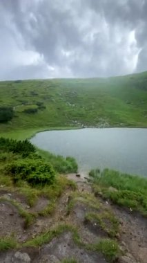 happy woman in yellow raincoat looking at mountain lake overcast hard weather condition