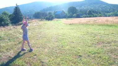 little girl making acrobatic wheel at green filed mountains on background summertime