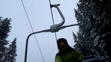 Kayak asansöründeki mutlu snowboardcu kış tatilinde selfie çekiyor.