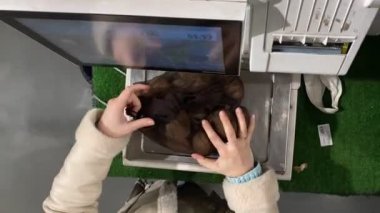 Genel bir bakış açısı olan bir kadın patates çuvalını ölçeğe koyuyor. Barkod alışverişi için fiyat etiketi alıyor.