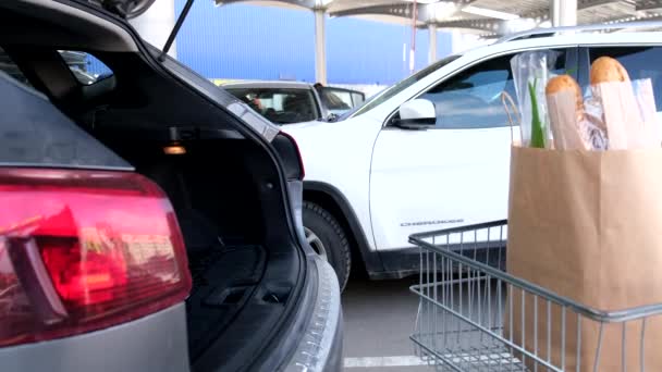 女人把食品杂货购物袋放进汽车行李箱商场的停车位 — 图库视频影像
