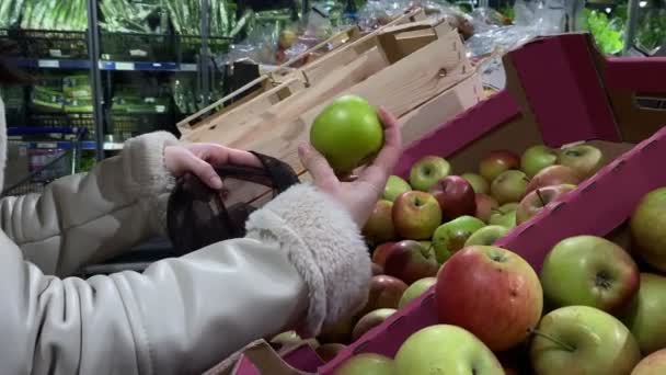 妇女在食品店挑选苹果时 把它放进手提包里 — 图库视频影像