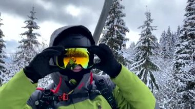 Kayak asansöründeki mutlu snowboardcu kış tatilinde selfie çekiyor.