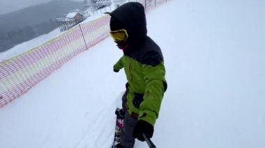 Kayak yapan snowboardcu kayak pistinde bulutlu bir havada selfie çekiyor.