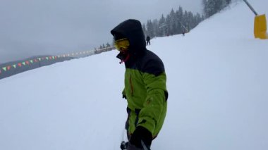Kayak yapan snowboardcu kayak pistinde bulutlu bir havada selfie çekiyor.