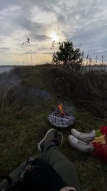 Çift, arka plandaki eğlence etkinliklerinde BBQ yangın uçurtmacılarının yanında dinleniyor.