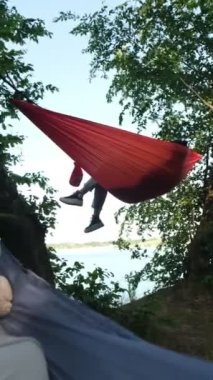 Pov adam göl manzaralı kamp alanı ile hamakta yatıyor.