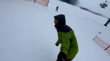 Kayak yapan snowboardcu kayak pistinde bulutlu bir havada selfie çekiyor.