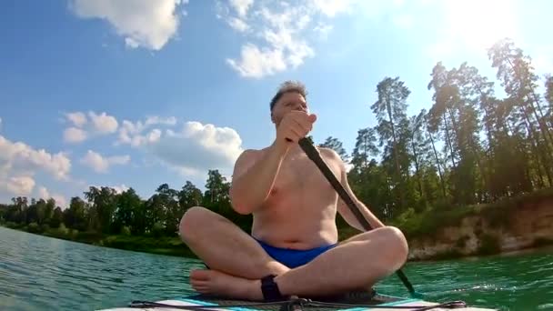 澄んだ湖の水の上に座っている男は — ストック動画