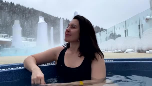 在冬日雪地温泉度假胜地的户外按摩浴缸里 一个微笑的女人的画像 — 图库视频影像