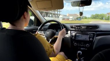 Sarı elbiseli kadın direksiyon tutan araba kullanıyor.