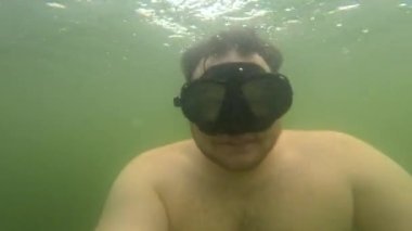 Scuba maskeli göl aktivitelerinde selfie çeken bir adam.