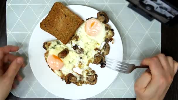 電話でビデオを見ている揚げ卵を食べるオーバーヘッドビュー — ストック動画