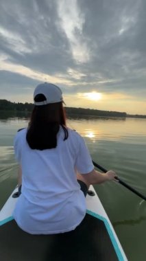 Gün batımında güvertede olan kadın göl aktiviteleri