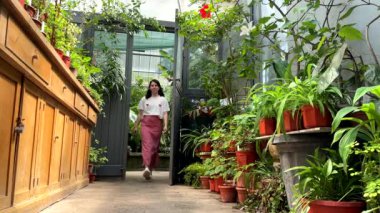 Güzel bir kadın botanik bahçesinde yürüyor bitkilerin tadını çıkarıyor.
