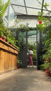 Güzel bir kadın botanik bahçesinde yürüyor bitkilerin tadını çıkarıyor.