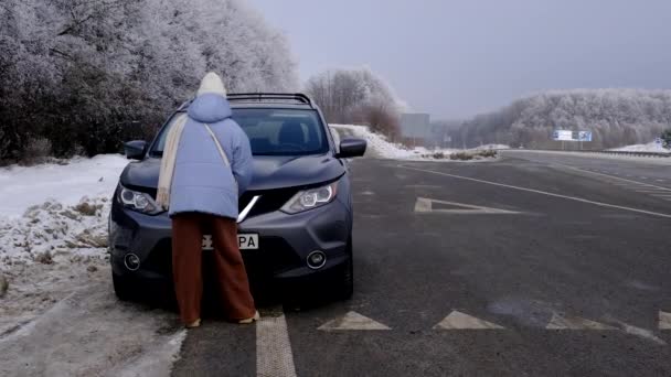 Kobieta Otwierająca Maskę Samochodu Sezonie Zimowym Przy Drodze — Wideo stockowe
