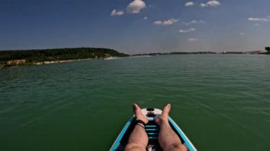Pov adam güneşli yaz gününde gölün üstünde dinleniyor. Arka planda su motosikleti var.