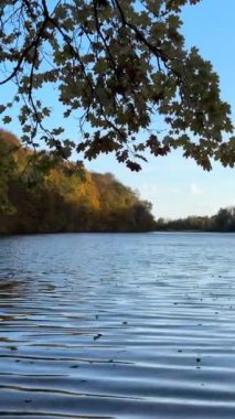 Sonbahar Gölü 'nün ortasında arka planda renkli ormandaki insan manzarası