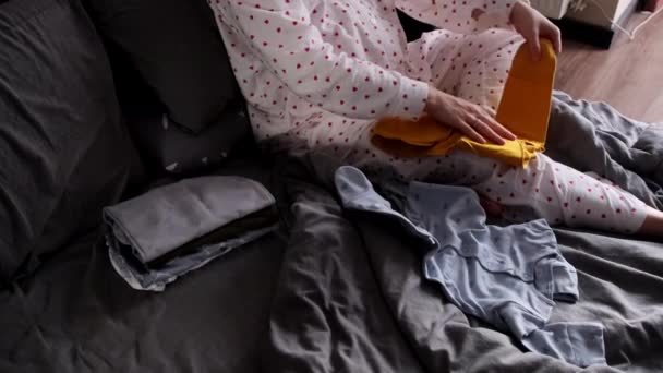 Glücklich Schwangere Frau Sieht Niedliche Babykleidung Die Bett Liegt Stockvideo