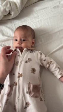 Uzanan bir bebeğin yakın çekimi, merakla onları işaret eden bir parmağa bakıyor..