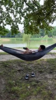 Baba ve oğul göl kenarında bir hamakta dinleniyorlar.